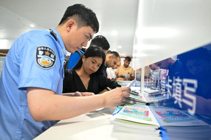 Nhân viên an ninh tại sân bay Thiên Tân của Trung Quốc hướng dẫn hành khách làm thủ tục nhập cảnh ngày 27/8. Ảnh: Xinhua