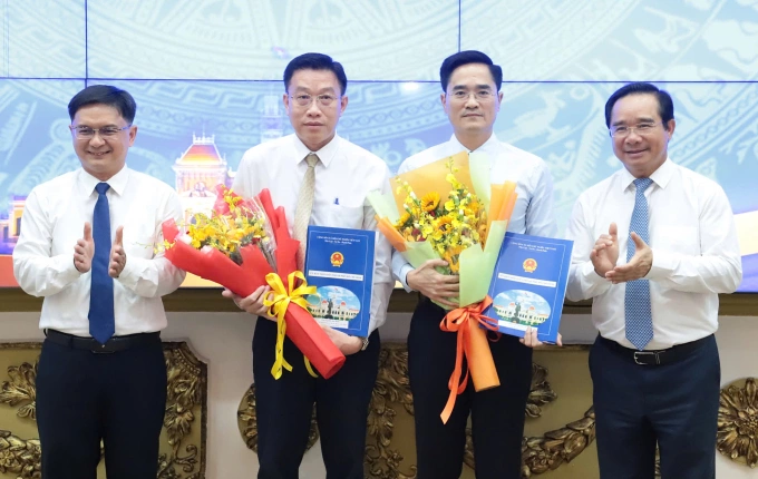 Ông Trần Quang Lâm (thứ hai, phải qua) và ông Nguyễn Anh Minh (thứ hai, trái qua) nhận quyết định từ lãnh đạo UBND TP HCM. Ảnh: Lê Tuyết