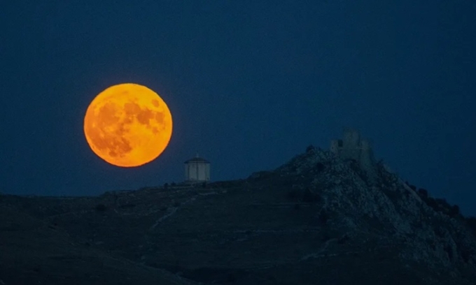Trăng mùa gặt mọc sau lâu đài Rocca Calascio ở Abruzzo, Italy vào ngày 1/10/2020. Ảnh: Lorenzo Di Cola/NurPhoto