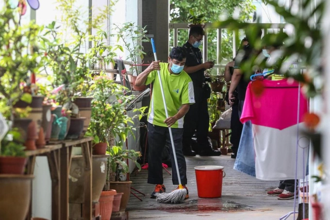 Nhân viên dọn dẹp hành lang bên ngoài căn hộ ở tầng 5 sau án mạng. Ảnh: Lianhe Zaobao