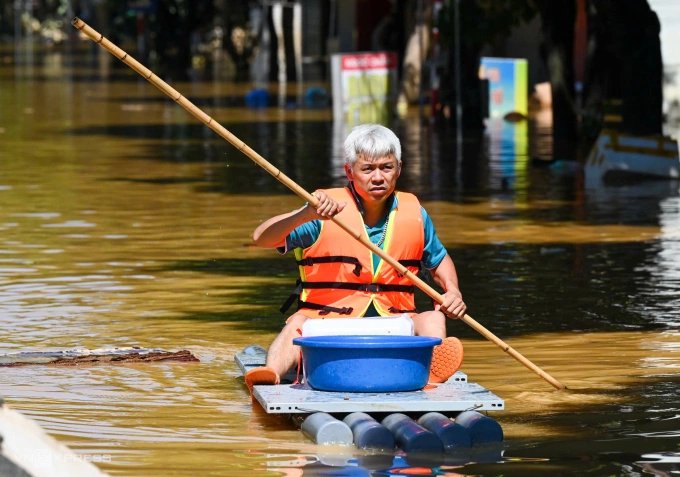 Người dân chèo thuyền mang đồ tiếp tế trên phố Minh Cầu, trung tâm tỉnh Thái Nguyên. Ảnh: Giang Huy