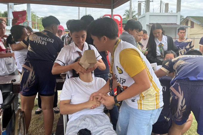 Sinh viên hỗ trợ bạn học bị thương ra ngoài sau rung chấn tại miền nam Philippines ngày 10/10. Ảnh: AFP