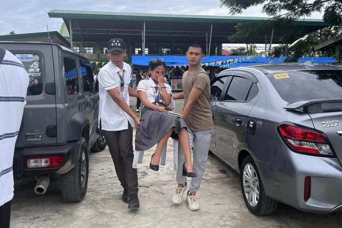 Sinh viên hỗ trợ bạn học bị thương ra ngoài sau rung chấn tại miền nam Philippines ngày 10/10. Ảnh: AFP