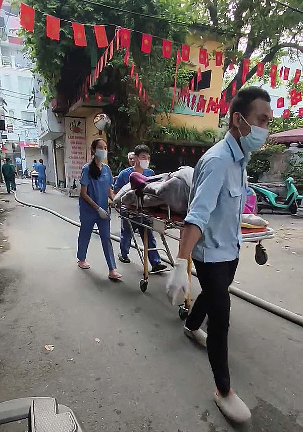 Thi thể được bọc kín bằng chăn đưa ra ngoài. Ảnh: Huy Mạnh