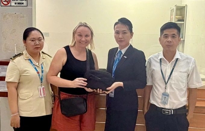 Đại diện Cảng hàng không quốc tế Phú Quốc trao trả túi xách đánh rơi cho du khách người Úc. Ảnh: Dương Đông
