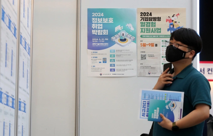 Một nam thanh niên tìm kiếm thông tin tuyển dụng tại hội chợ ở Seoul hồi tháng 5. Ảnh: Korea Herald