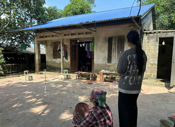 Mẹ con bà Liên trước căn nhà nứt tường không thể ở sau lũ, tháng 10/2025. Ảnh: Phong Linh