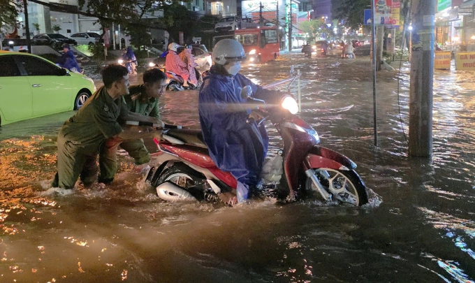 Lực lượng công an hỗ trợ người dân qua khu vực ngập sâu tại trung tâm Cần Thơ. Ảnh: An Bình