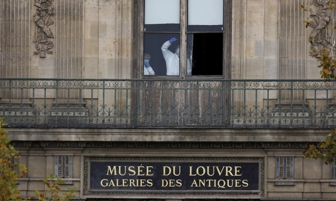 Các thành viên của đội pháp y kiểm tra một cửa sổ tại bảo tàng Louvre sau vụ cướp hôm 19/10. Ảnh: Reuters