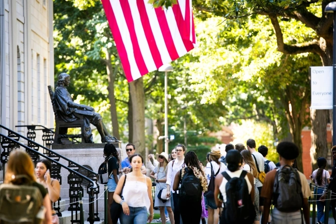 Sinh viên đi qua tượng đài John Harvard trong khuôn viên. Ảnh: Harvard University Fanpage