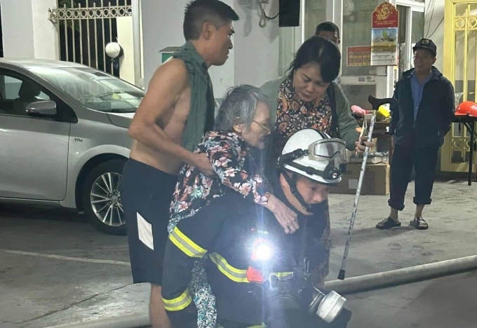 Cụ bà được đưa thoát khỏi đám cháy. Ảnh: Anh Tuấn