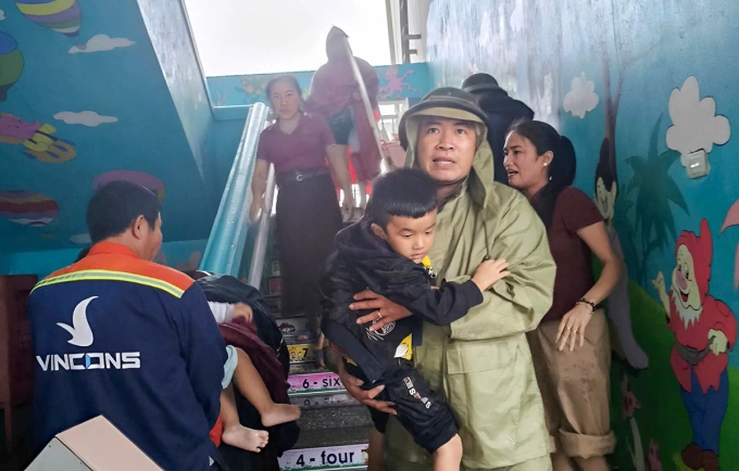 Phụ huynh đón con về nhà sau khi trường Mầm non ở tổ dân phố Tây Yên bị ngập, trưa 30/10. Ảnh: Hùng Lê