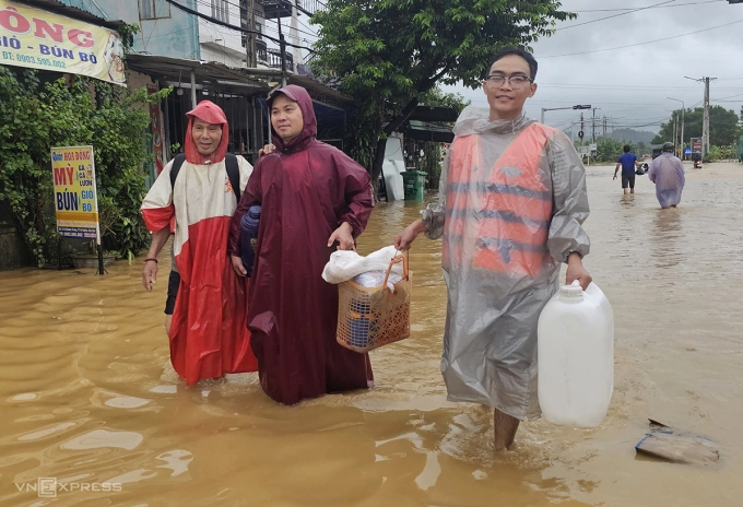 Ông Lê Duy Hòa bên trái cùng hai người con lội nước lũ đưa cơm cho bà Lê Thi Ba. Ảnh: Đắc Thành