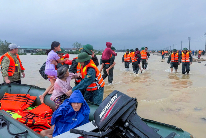 Lực lượng chức năng dùng cano di chuyển các hộ dân sống ở vùng thấp trũng đi tránh trú, trưa 31/10. Ảnh: Hùng Lê
