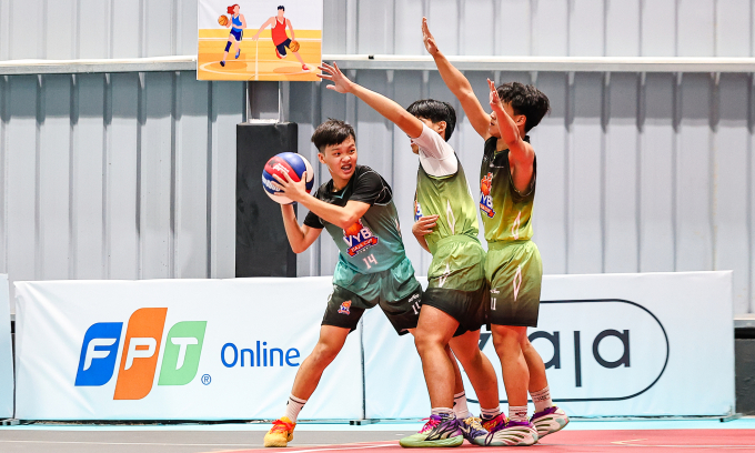 Nguyễn Đình Nguyên - THPT Nguyễn Tất Thanh (áo 14, xanh ngọc) tranh chấp với hai cầu thủ THPT Nguyễn Thị Minh Khai. Ảnh: VYB