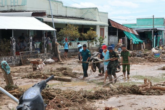 Lực lượng địa phương đang khiêng xe máy bị cuốn trôi của người dân lên đường. Ảnh: Việt Quốc
