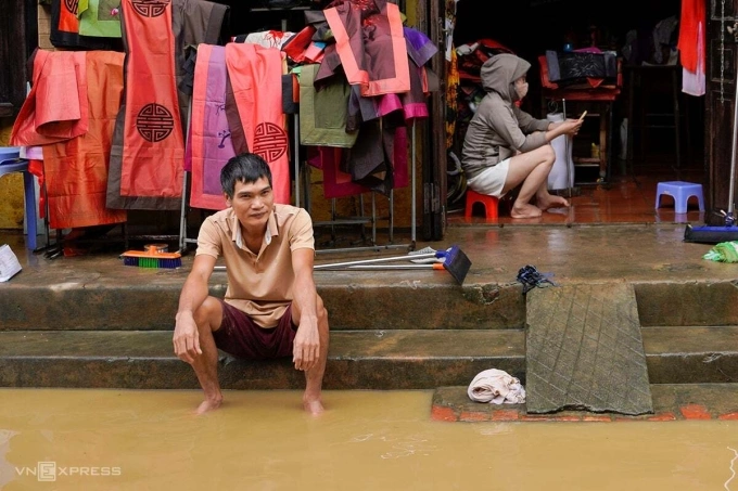 Anh Trịnh Mạnh Tường, chủ cửa hàng đồ lưu niệm, quần áo lụa trên đường Nguyễn Thái Học, mệt mỏi dọn lũ hôm 31/10. Hiện lũ lên lại trên tuyến đường này từ đêm 2/11. Ảnh: Nguyễn Đông
