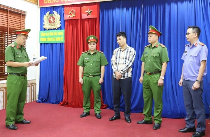 Công an tống đạt quyết định khởi tố với Giám đốc Phan Văn Kiếm (áo kẻ). Ảnh: Công an cung cấp