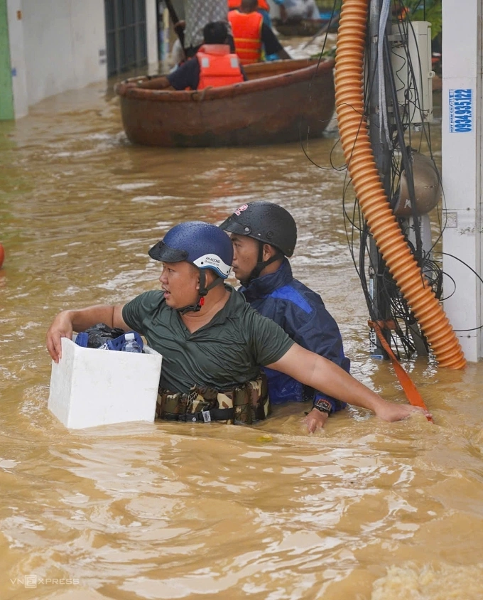 Một số người dân ở phường Tây Nha Trang, Khánh Hòa, dùng thùng xốp, phao tự chế luồn lách bên những trụ điện để thoát ngập. Ảnh: Bùi Toàn