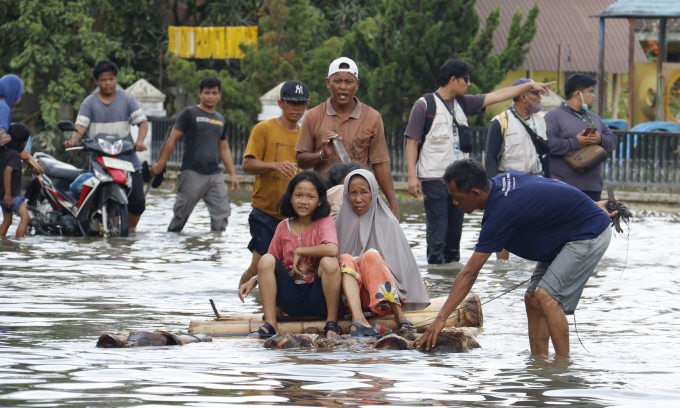 Người dân di chuyển qua khu vực lũ lụt ở Bắc Sumatra hôm 6/12. Ảnh: AFP