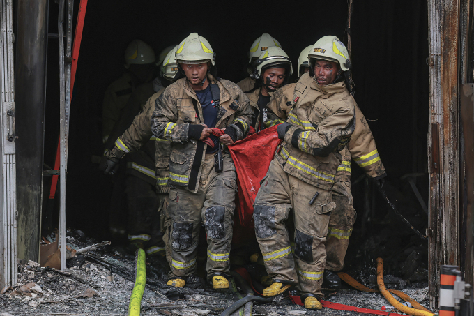 Lính cứu hỏa đưa thi thể một nạn nhân khỏi tòa nhà bị hỏa hoạn. Ảnh: AFP