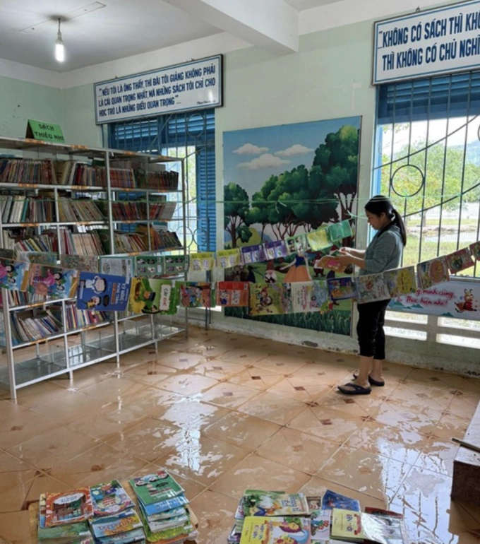 Cô giáo tại trường TH Cam Hoà 1 đang phơi sách vở của học sinh bị ngâm nước. Ảnh: Nhà trường cung cấp