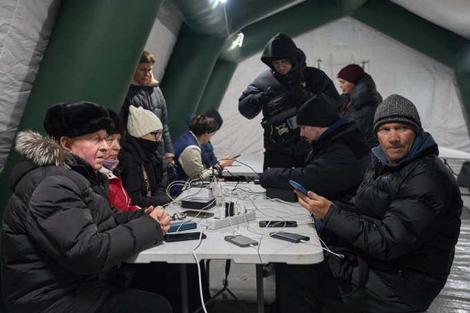 Người dân Kiev sưởi ấm và sạc điện thoại trong một lều trú ẩn khẩn cấp dựng ngoài khu chung cư tại Kiev ngày 21/1. Ảnh: AP