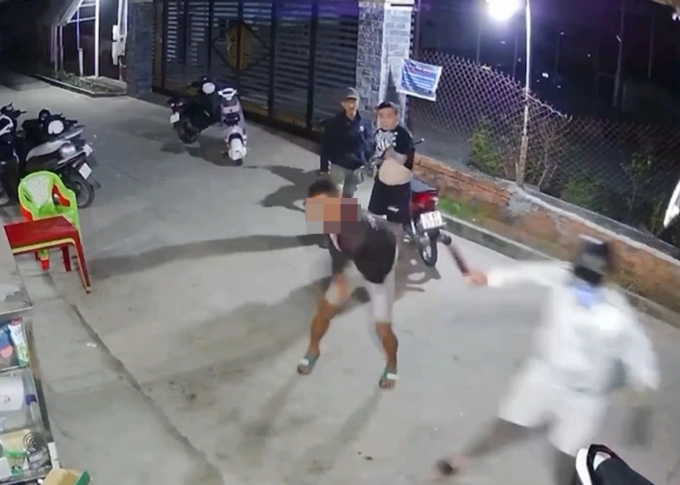 Trần Dương Hoàng (áo trắng, đội nón bảo hiểm) cầm dao chém nạn nhân. Ảnh: Camera an ninh