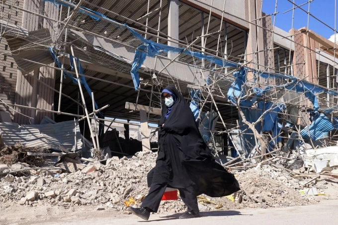 Người phụ nữ đi qua một công trình bị phá hủy gần quảng trường Ferdowsi ở Tehran ngày 3/3. Ảnh: AFP