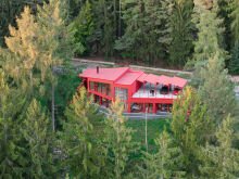 Biệt thự màu đỏ nổi bật giữa rừng, xe đỗ trên mái nhà