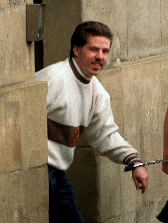 William Billy Dunlop tươi cười khi bị còng tay dẫn ra khỏi tòa án Newcastle sau phiên tòa đầu tiên vào năm 1991. Ảnh: NNP