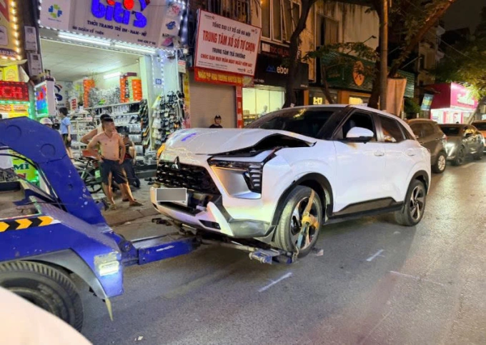 Cảnh sát cẩu chiếc xe gây tai nạn rời khỏi hiện trường. Ảnh: Việt An