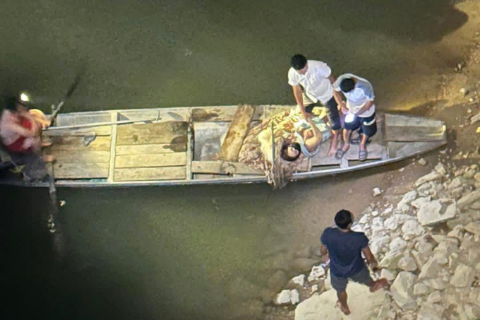 Người dân dùng thuyền gỗ hỗ trợ đưa hai nạn nhân vào bờ, tối 12/4. Ảnh: Hùng Lê