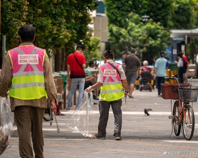 Ở Singapore, phạt tiền còn kèm đánh roi hoặc lao động công ích ở nơi công cộng, với trang phục dễ nhận diện với dòng chữ Corrective Work Order - lao động công ích ở sau lưng. Ảnh: National Environment Agency
