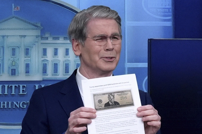 Bộ trưởng Tài chính Scott Bessent cầm mẫu thiết kế tờ tiền 250 USD có hình Tổng thống Donald Trump trong họp báo tại Nhà Trắng ngày 28/5. Ảnh: AP