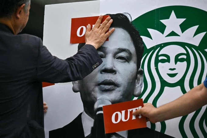 Những người biểu tình dán nhãn lên ảnh Chủ tịch Tập đoàn Shinsegae. Ảnh: AFP