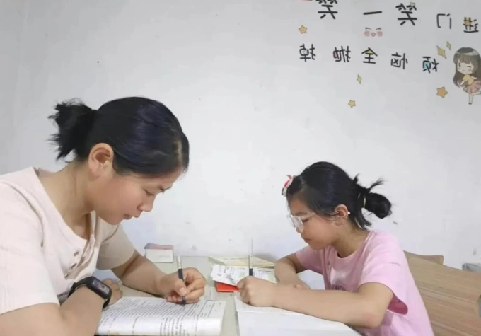 Lý Giai ôn tập cho kỳ tuyển sinh cao học bên cạnh con gái đang làm bài tập về nhà. Ảnh: SCMP