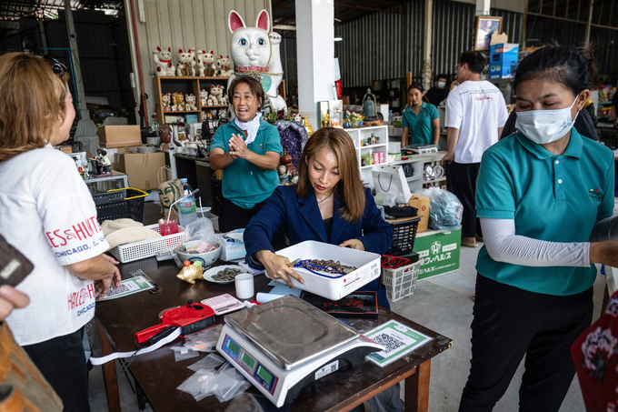 Chủ tiệm Wipaporn Je Nana Sakdisakwasdi cân đồ trang sức cho khách trong cửa hàng bán hàng bãi Nhật Bản của cô tại Nonthaburi, ngoại ô Bangkok, ngày 30/5. Ảnh: AFP