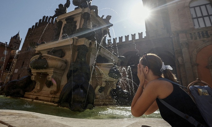 Một phụ nữ rửa mặt tại đài phun nước Neptune ở Bologna, Italy. Ảnh: Reuters
