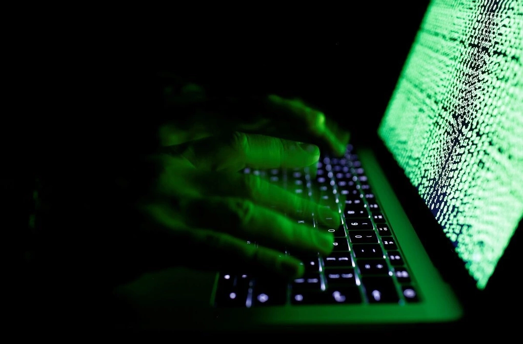 Một người đàn ông gõ phím máy tính với màn hình hiển thị các dòng code. Ảnh: Reuters