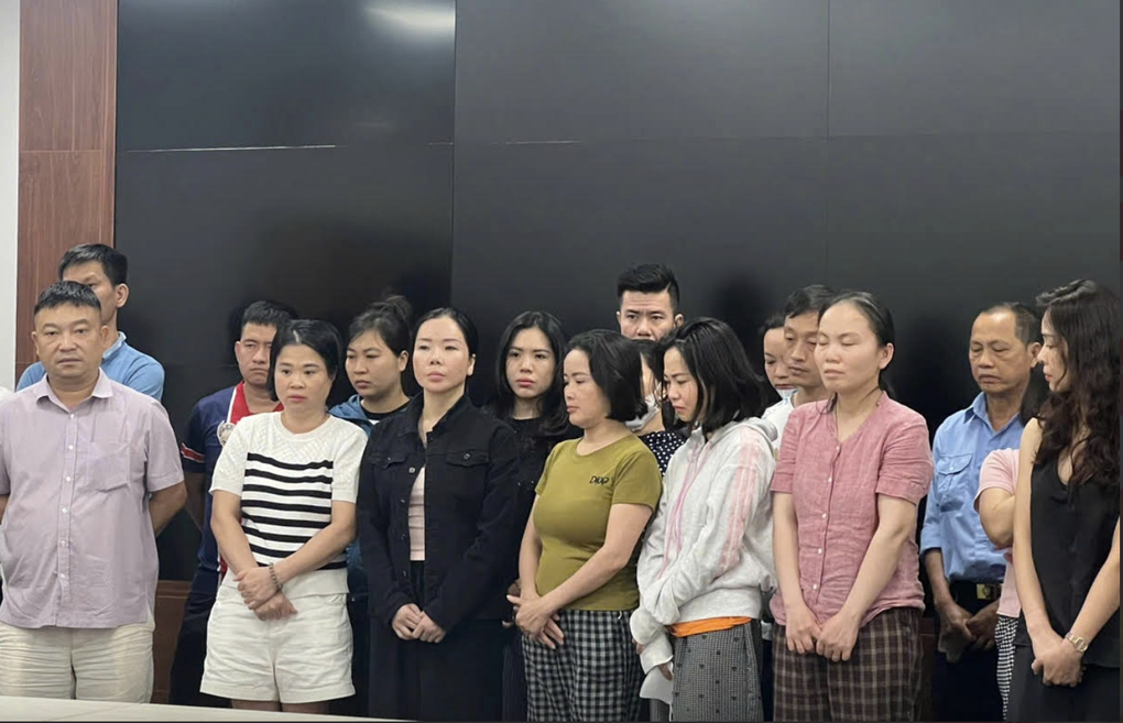 Cựu Viện trưởng Trần Văn Trường (trái), Mai Anh (áo đen thứ 3 hàng đầu trái) cùng các bị can khi bị bắt. Ảnh: Bộ Công an