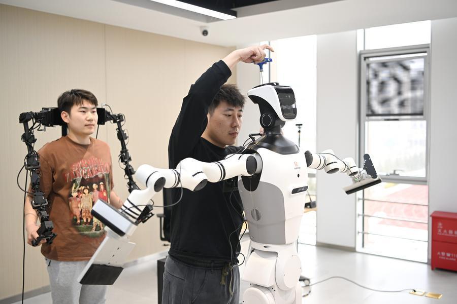 Hai huấn luyện viên đang điều chỉnh một robot hình người ở khu Hùng An, tỉnh Hà Bắc. Ảnh: Tân Hoa Xã