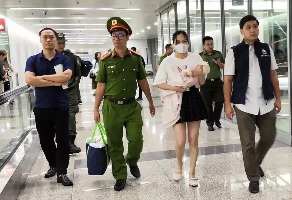 Ngô Thị Thêu bế con nhỏ bị dẫn giải về nước hôm 15/8/2025. Ảnh: Bộ Công an